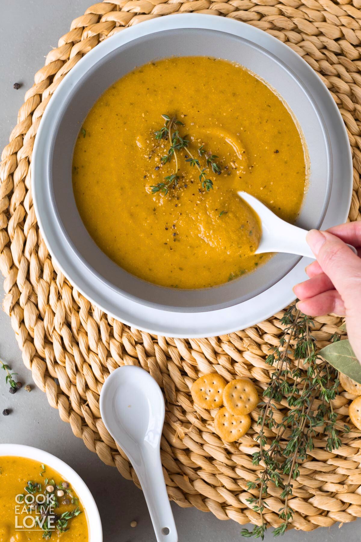 Bowl of carrot and cauliflower soup with hand dipping in spoon