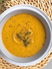 White bowl with carrot soup on table