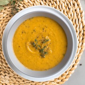 White bowl with carrot soup on table