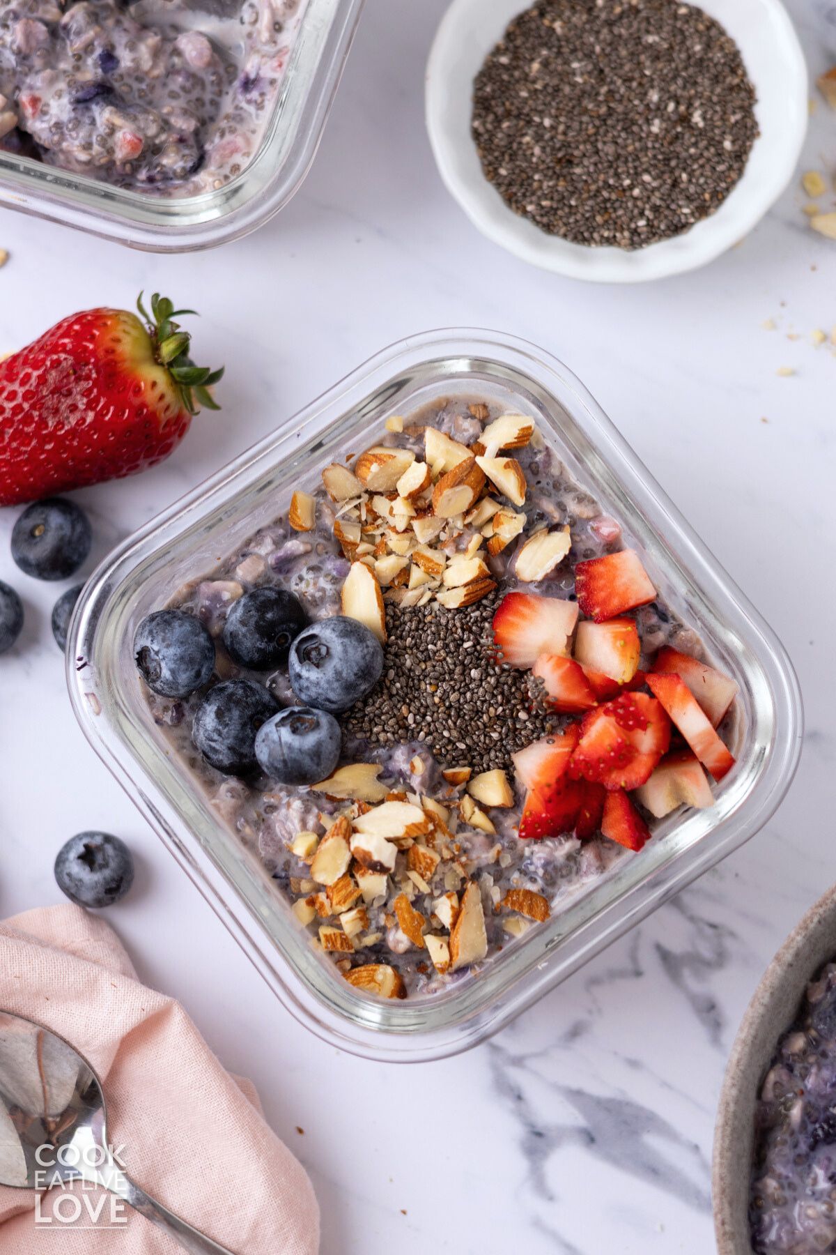 Berry chia seed overnight oats in a glass container with toppings added.