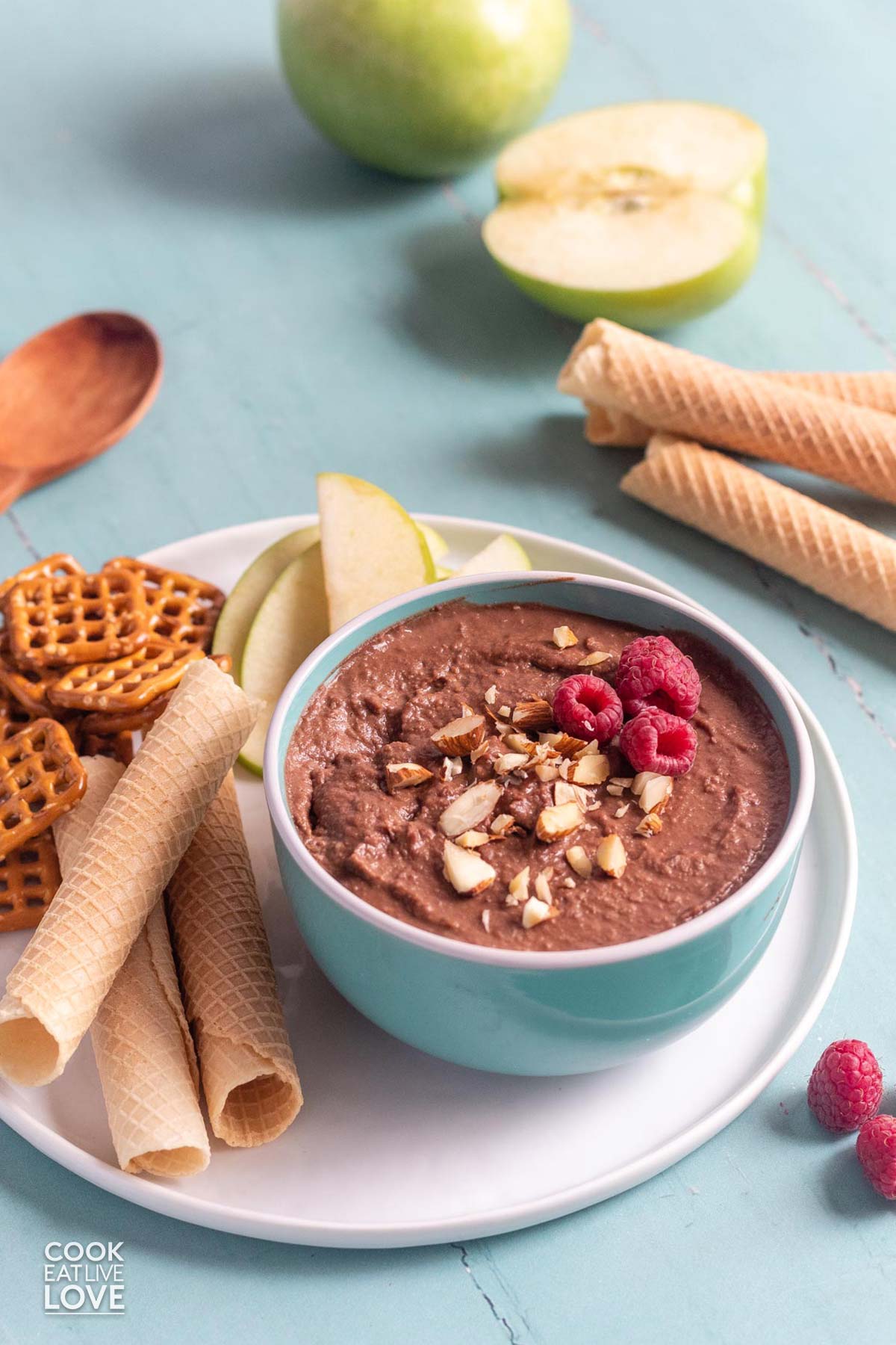 Chocolate dessert hummus in a bowl on a table with fruit and cookies.