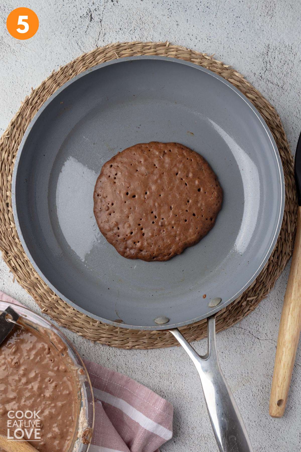 Chocolate protein pancake poured into a skillet and partially cooked.