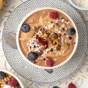 Chocolate smoothie bowl with bananas and lots of toppings in a bowl.