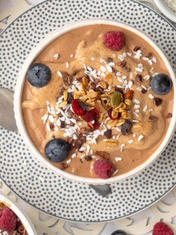 Chocolate smoothie bowl with bananas and lots of toppings in a bowl.