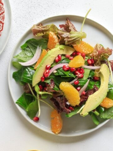Plate of salad and bowl of halved citrus on a table