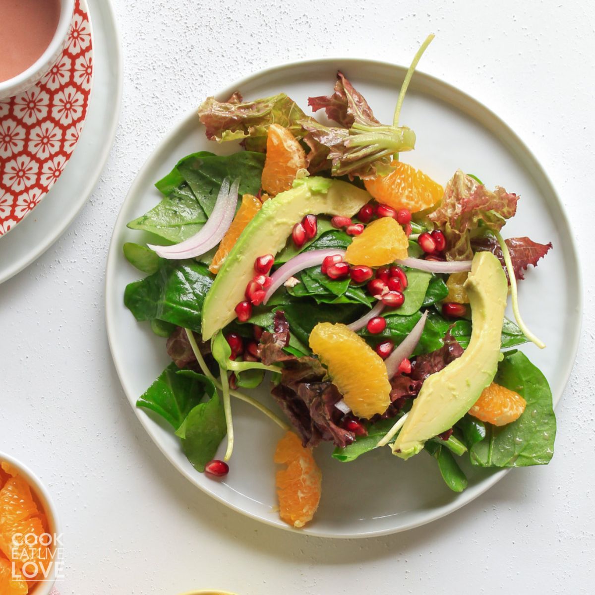 Plate of salad and bowl of halved citrus on a table 
