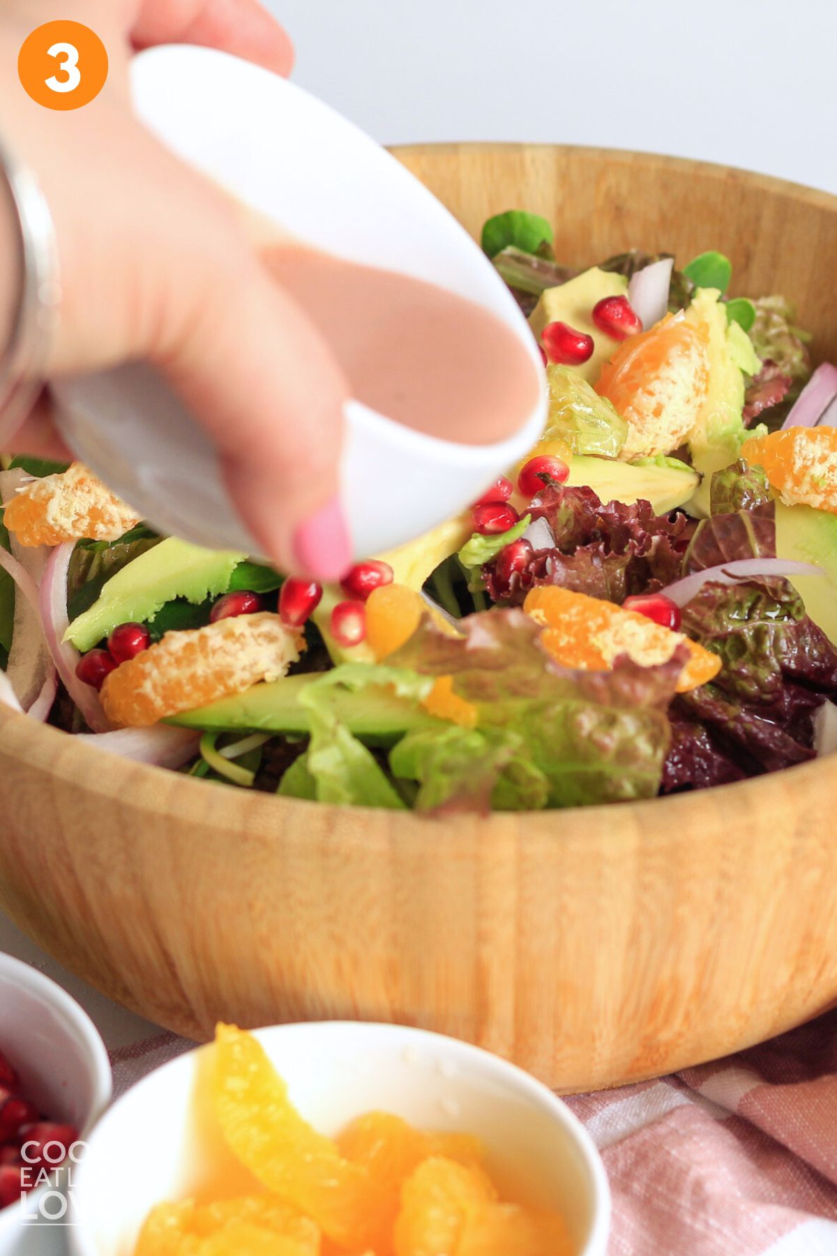 A hand pouring dressing on a salad.