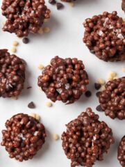 Dark chocolate quinoa bark shown in jar on gray backdrop with red and white packaging to use to give as gifts.