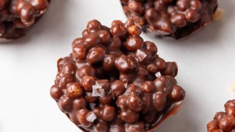 Quinoa chocolate bark in jar on gray backdrop with red and white packaging.