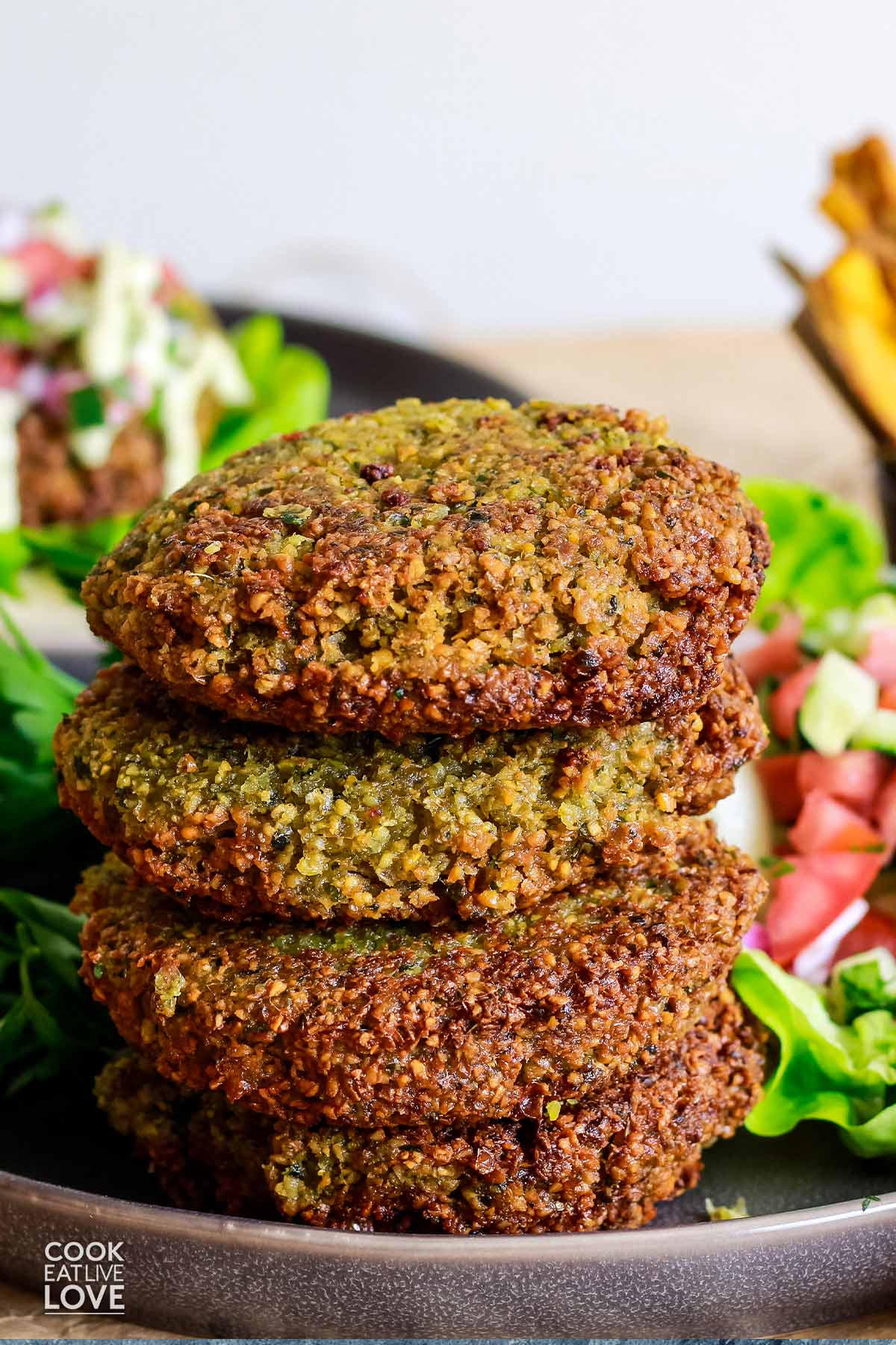 A stack of falafel burgers on a plate with some in the background.