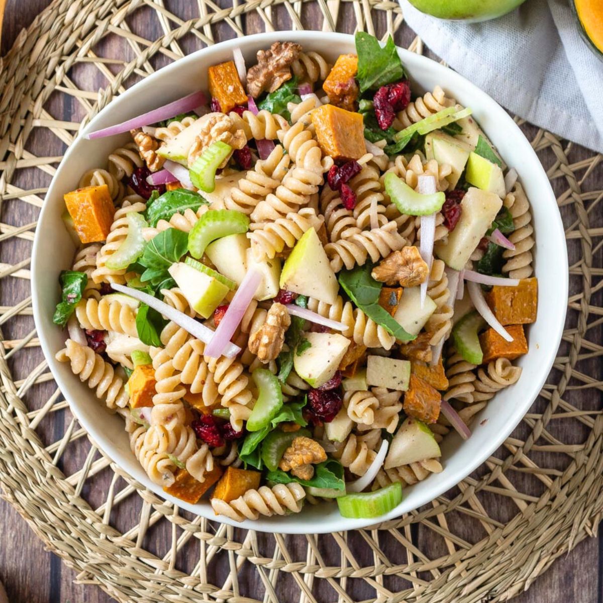 Fall pasta salad in white rectangle bowl with wooden serving spoons.