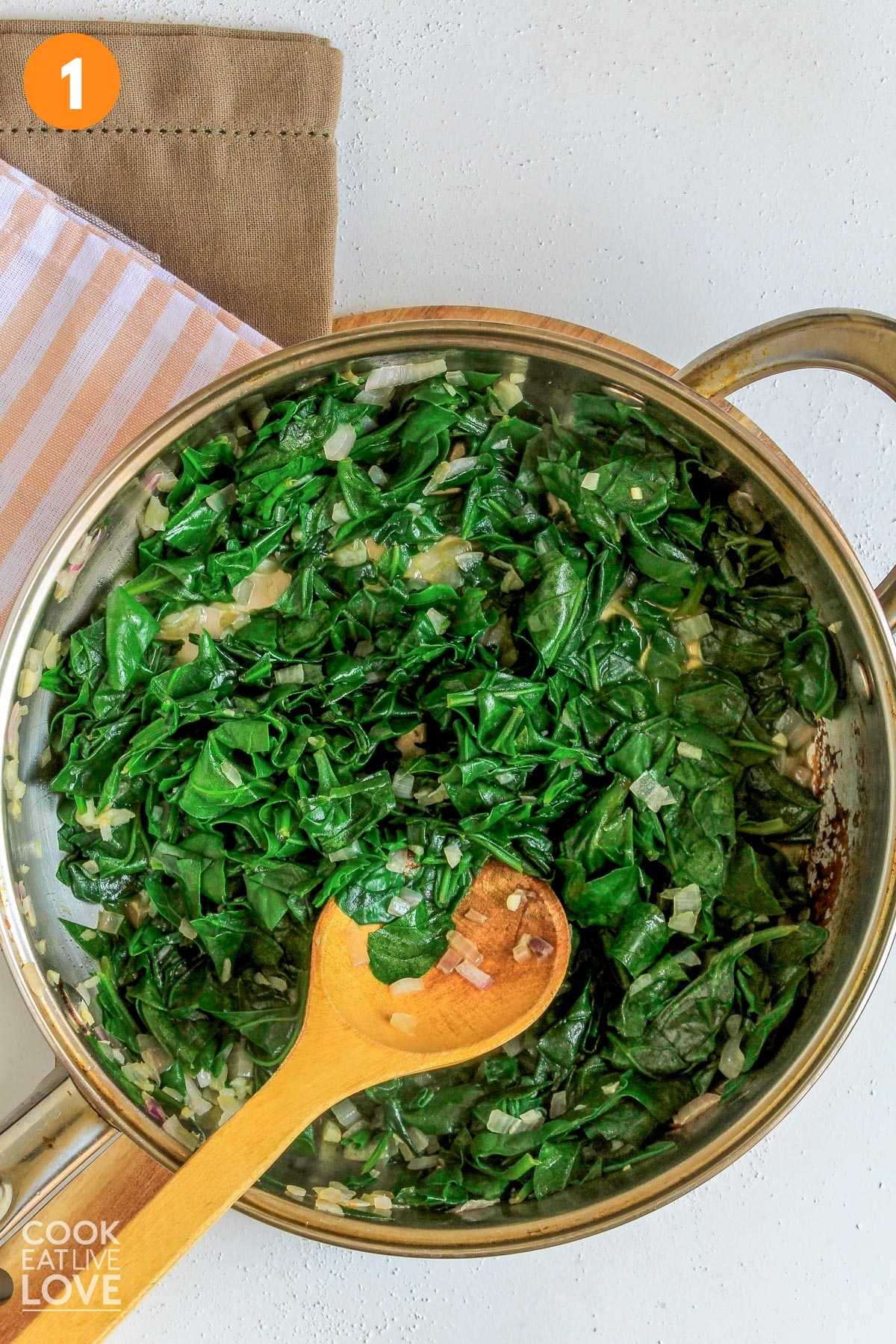 Pan of cooked spinach on table.