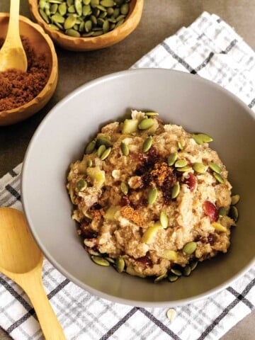 A bowl of healthy quinoa flake porridge sitting on a table on White And Gray Plaid napkin