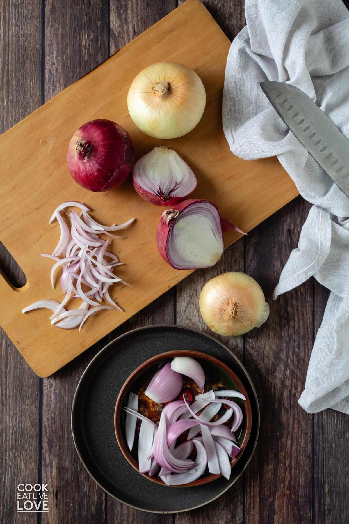 Red and yellow onions on a cutting board with some slices and one cut in half.