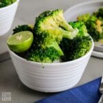 A bowl of instant pot broccoli on the table with a plate of more in the background.