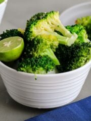 A bowl of instant pot broccoli on the table with a plate of more in the background.