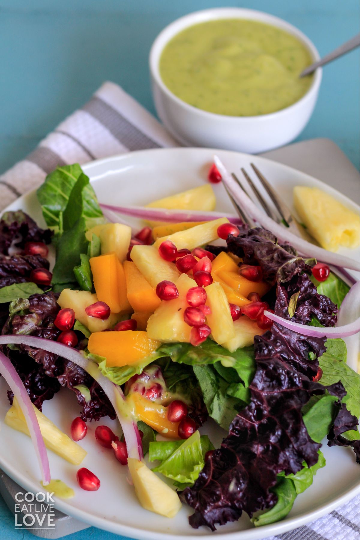 Mango salad on white plate with bowl of avocado dressing.