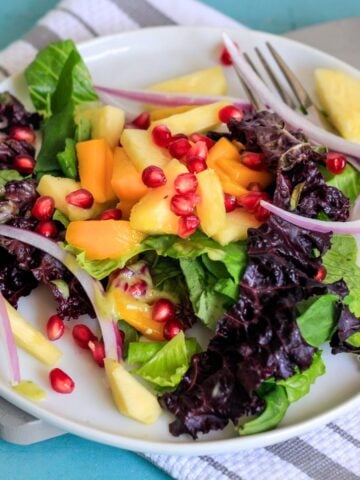 A mango avocado salad on a white plate with a gray and white napkin underneath it.