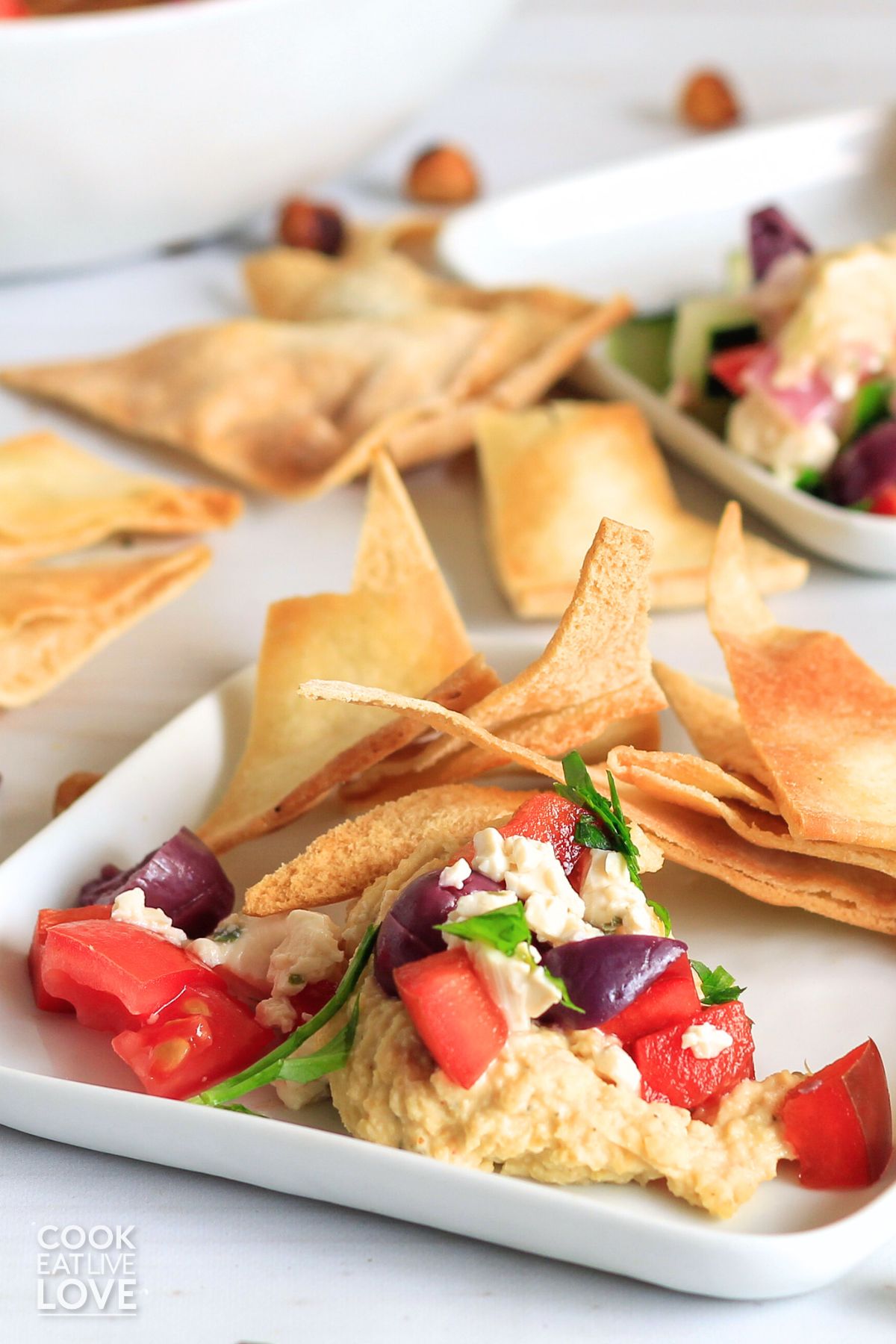 Easy vegan dip with mediterranean flavors served up on small white plates with pita chips.