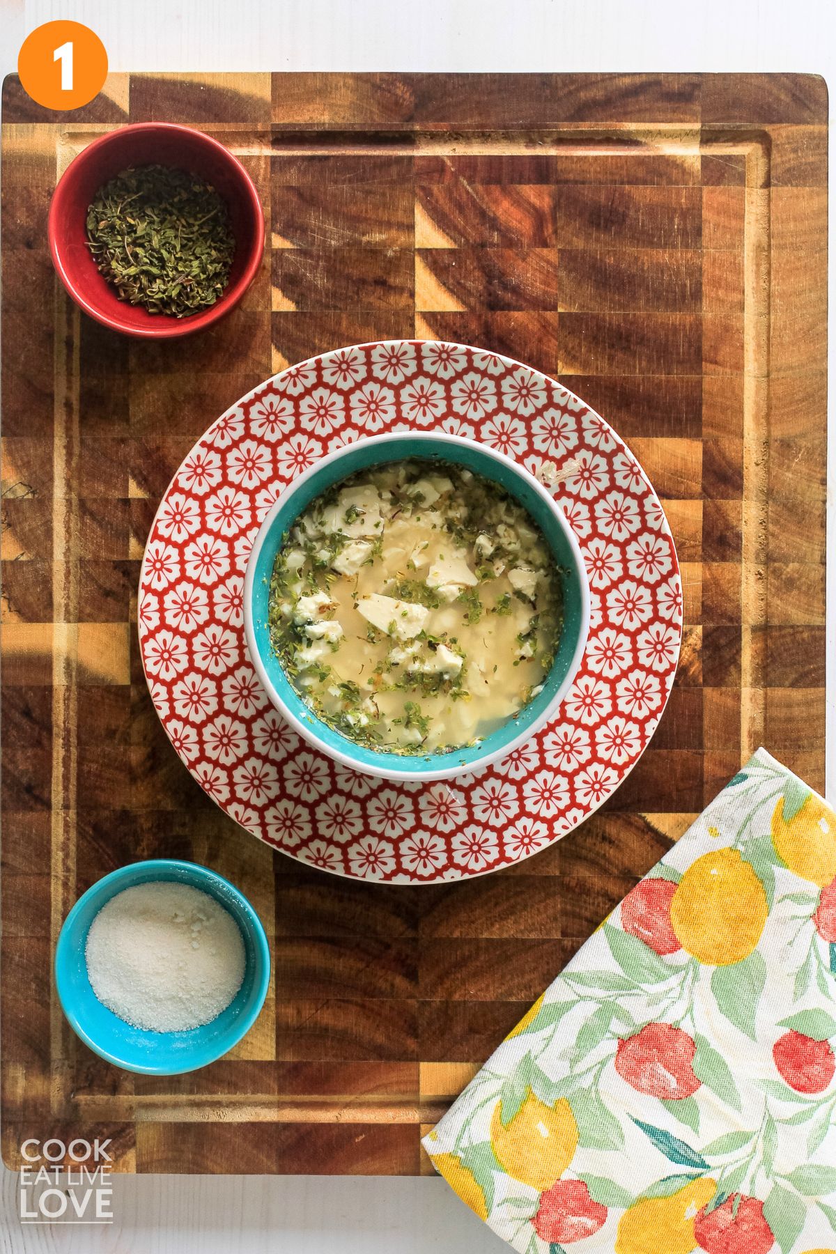 Hand adding oregano to crumbled tofu to make the tofu feta
