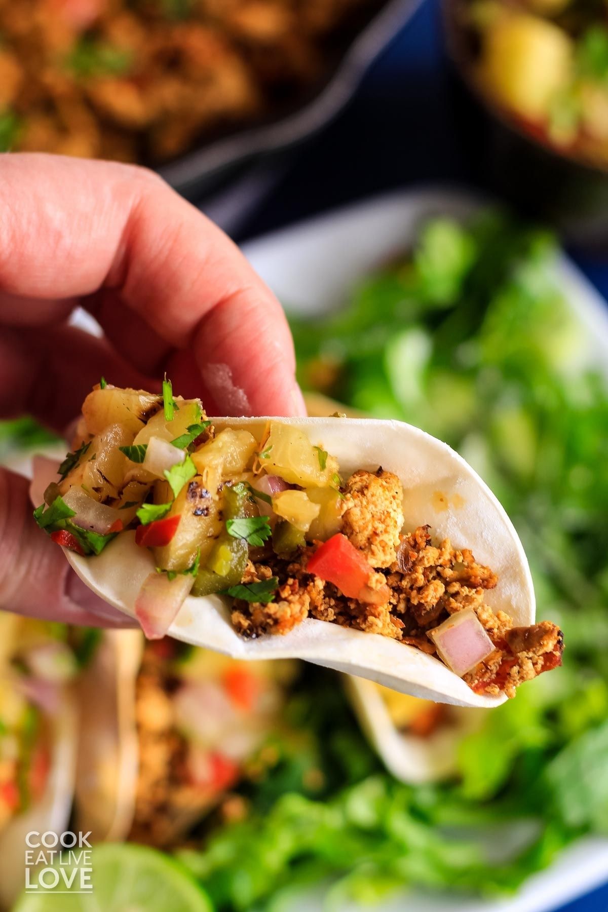 A hand holding up mini taco appetizer up over the plate.