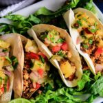 Mini tacos on a platter with shredded lettuce.
