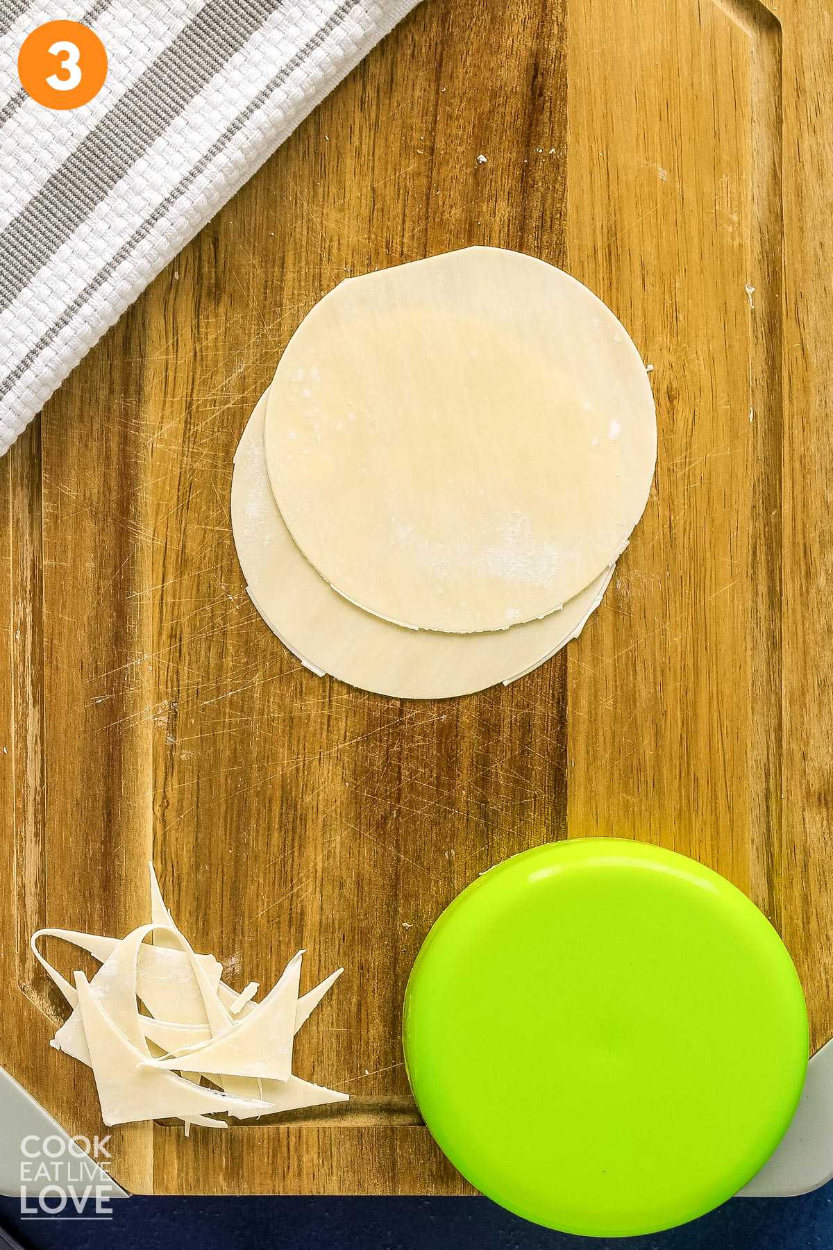 Wonton skins on cutting board made into round shape using a lid.