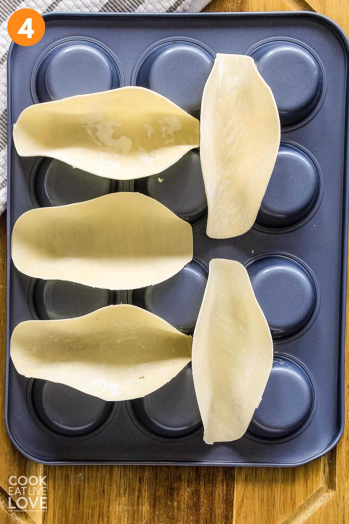 Round wonton skins are shown on upside down muffin tin to form a taco shell shape.