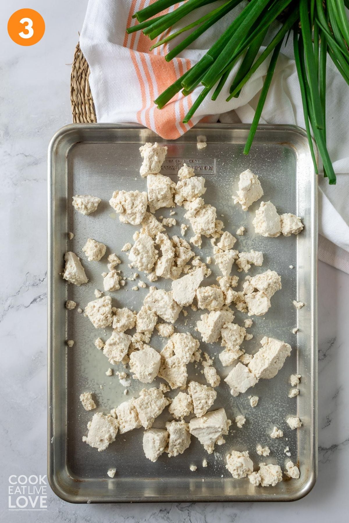 Tofu spread out on a pan to cook.