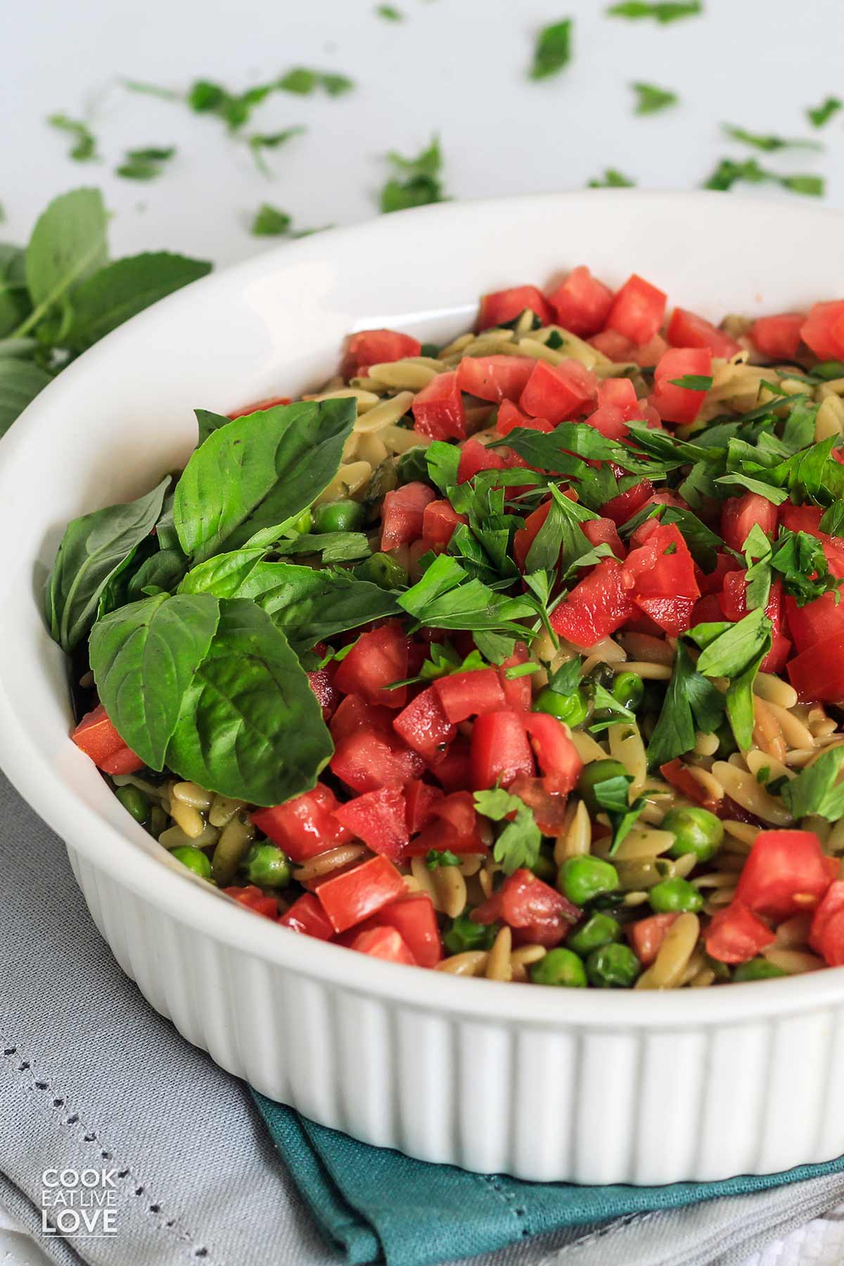 Pesto orzo in a serving bowl garnished with diced tomatoes.