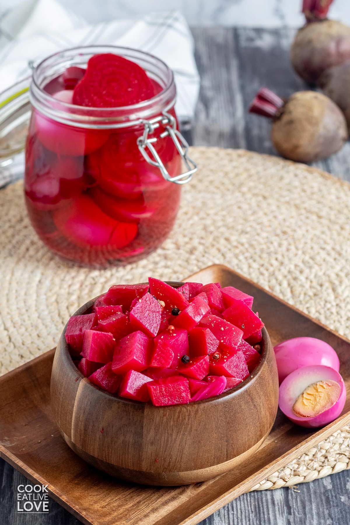 A bowl of diced pickled beets and some sliced in a jar in the back.