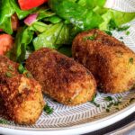Potato croquettes on plate with salad.