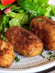 Potato croquettes on plate with salad.