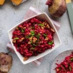 Raw beet salad served up in a white square bowl on the table.
