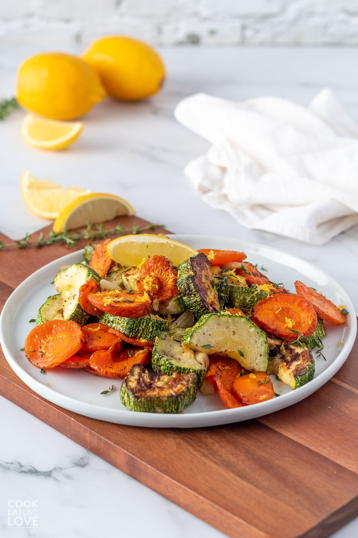 A white plate topped with zucchini and carrots sitting on a brown cutting board.