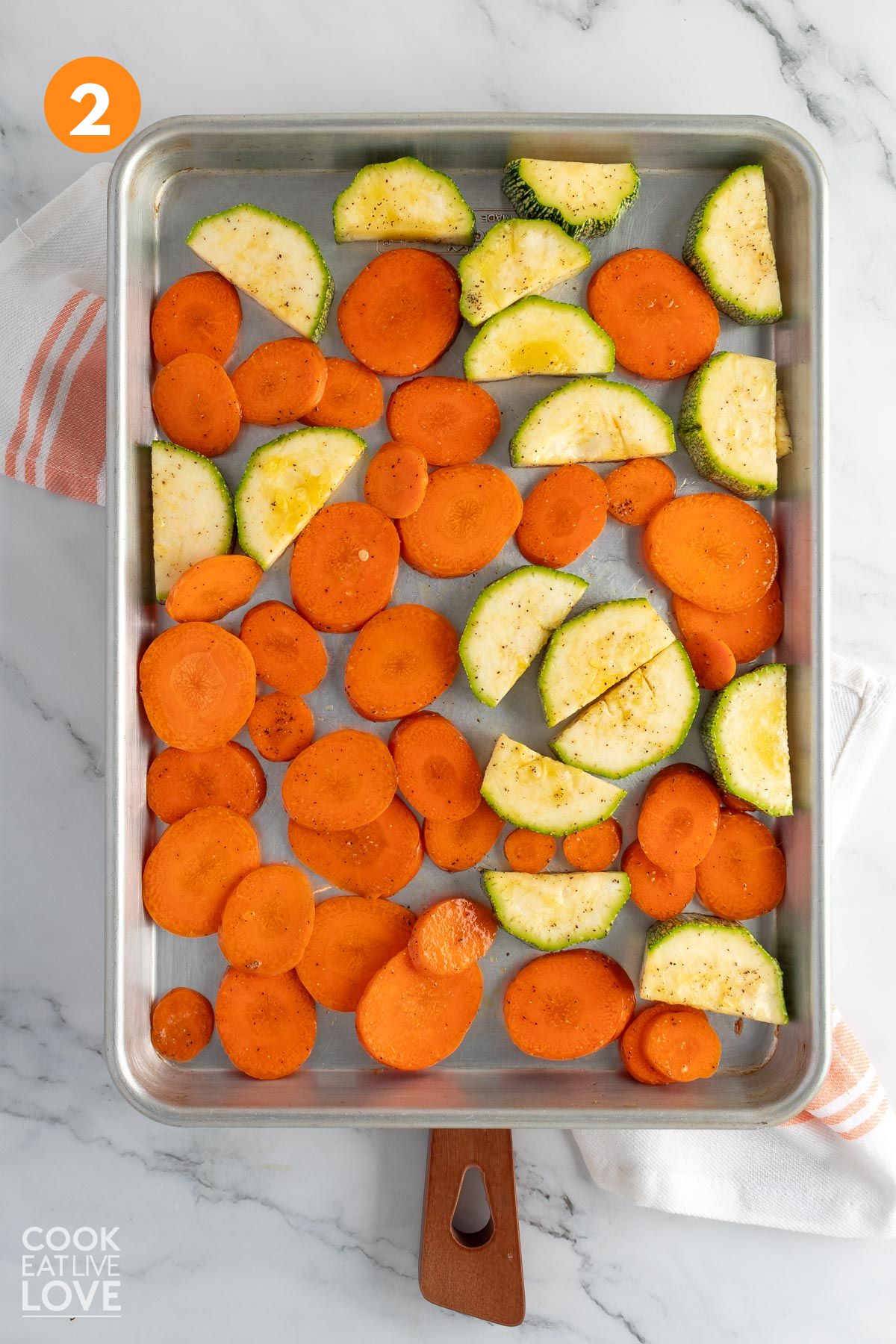 Zucchini and carrots spread out on a baking tray.