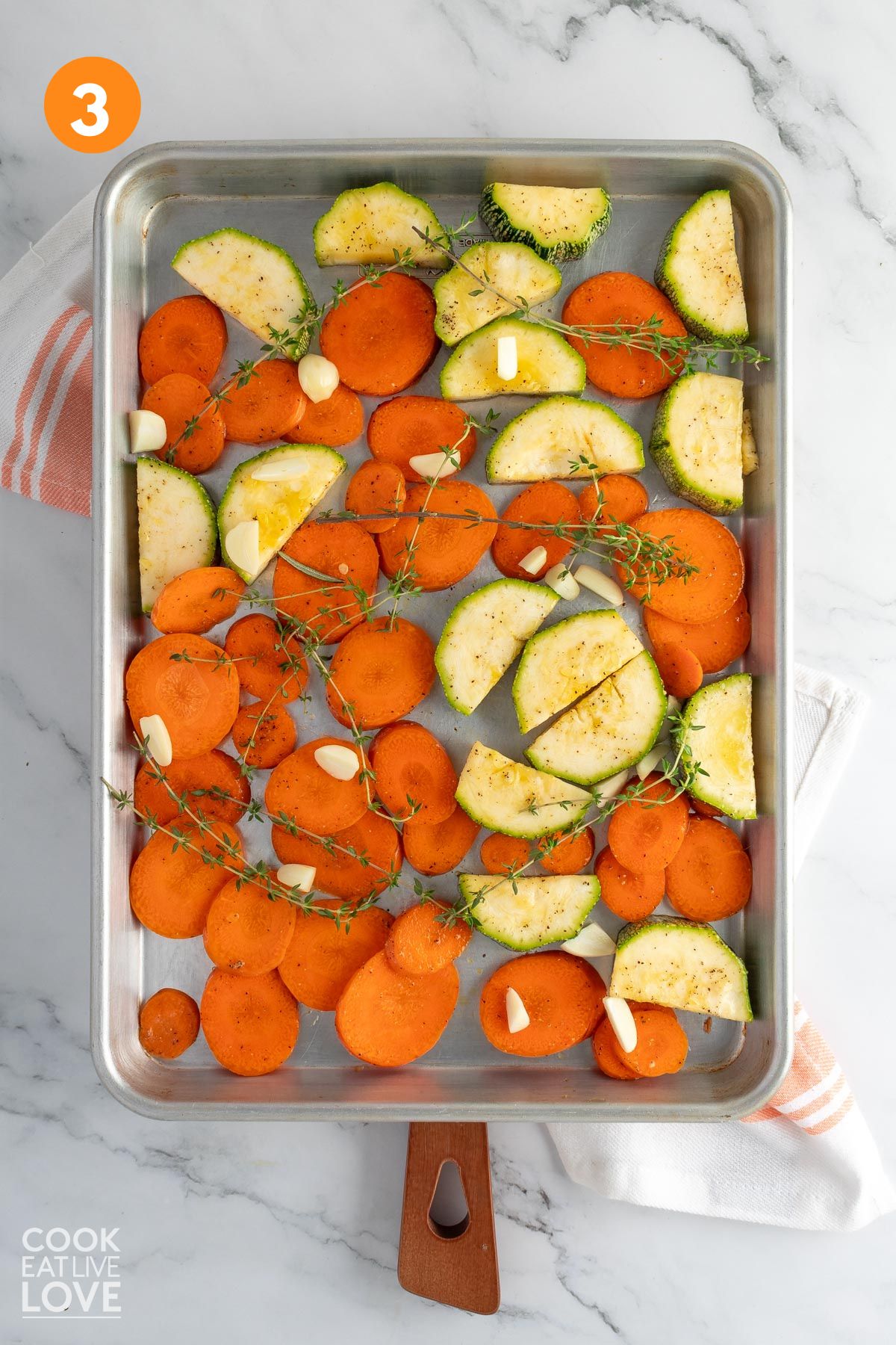 Zucchini and carrots on a baking tray with thyme and garlic.