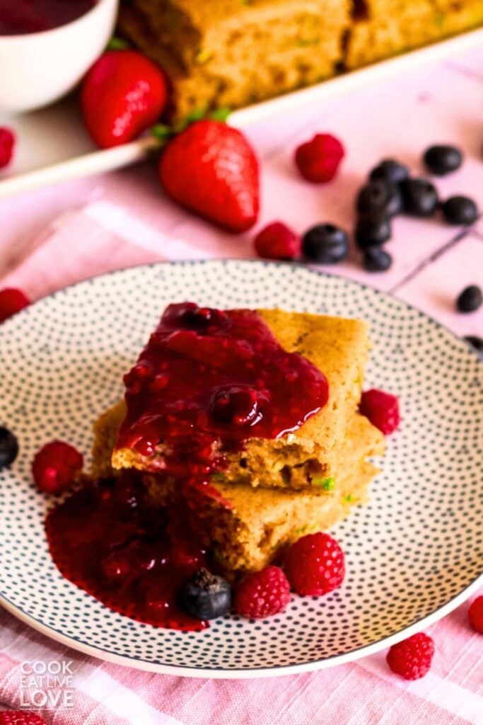 Two squares of sheet pan pancakes topped with berry mixture on a plate.