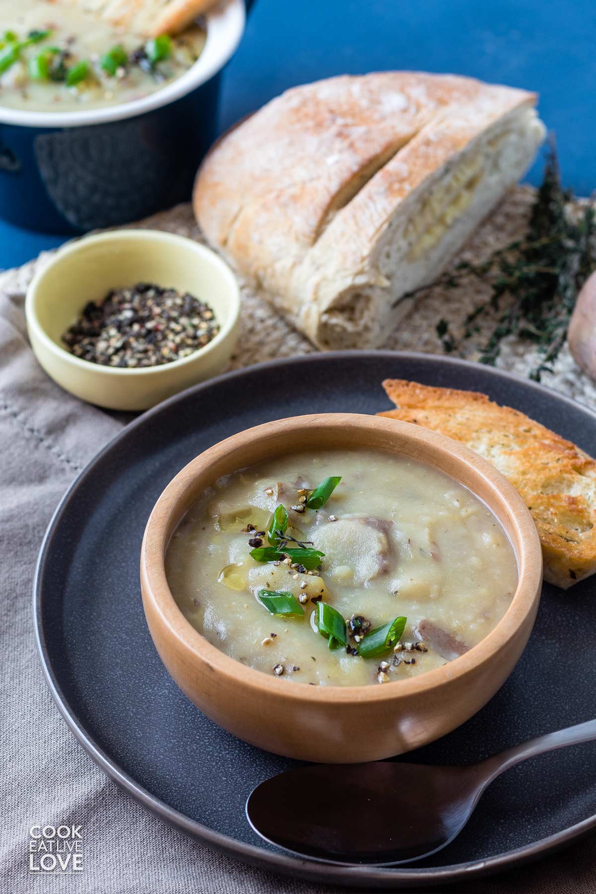 Potato and leek soup slow cooker served up in wooden bowl with bread