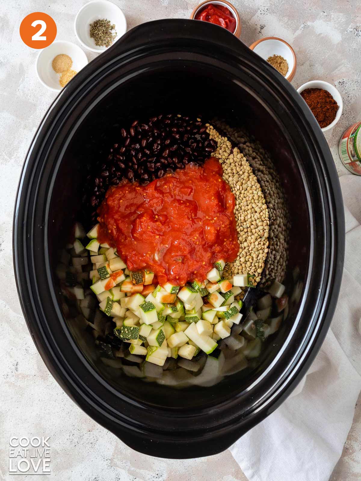Tomatoes, zucchini, lentils and beans in a slow cooker.