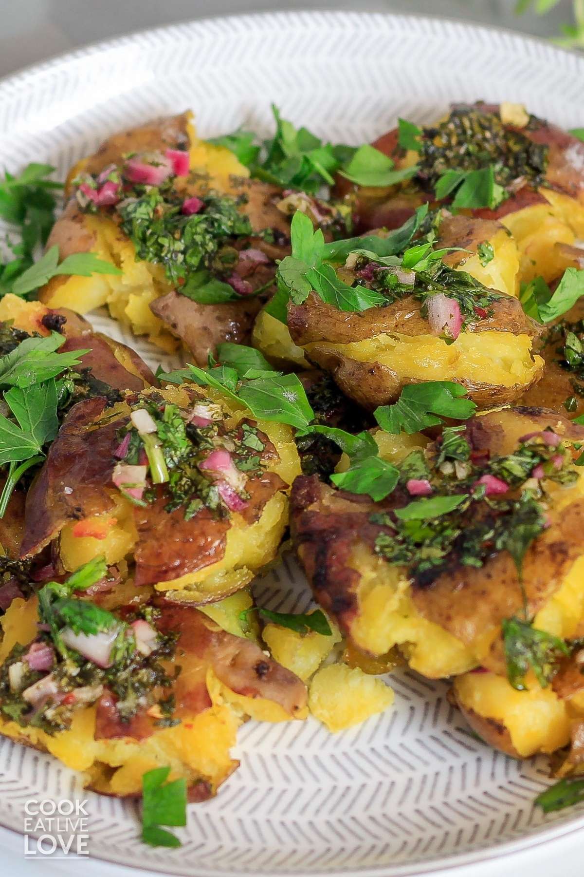 Plate of crispy potatoes served up on table and garnished with parsley.