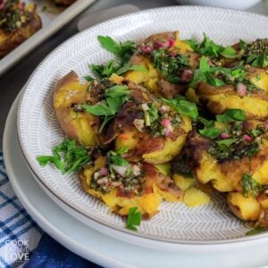 Crispy smashed red potatoes with chimichurri on a plate.