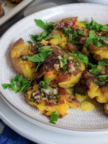 Crispy smashed red potatoes with chimichurri on a plate.