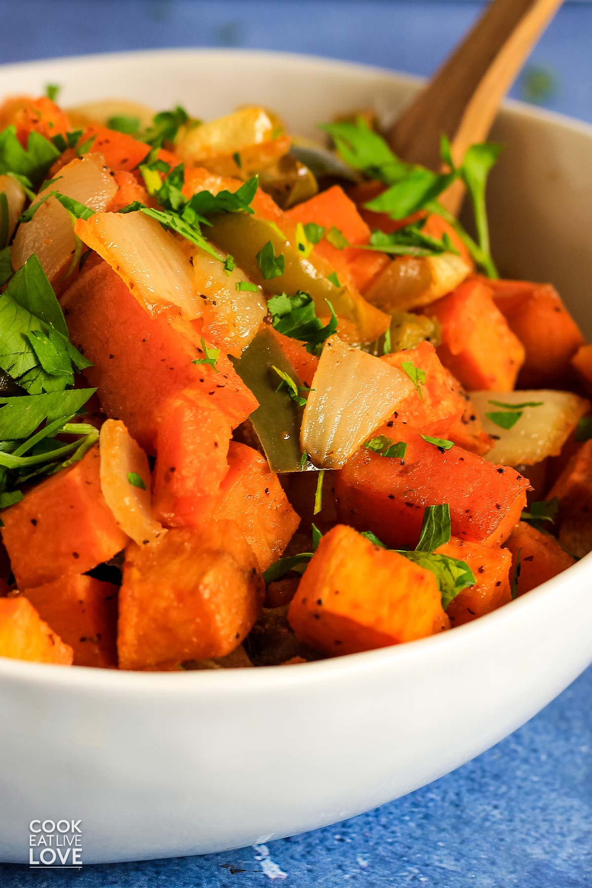 Sweet potato hash in a serving bowl with wooden spoon.
