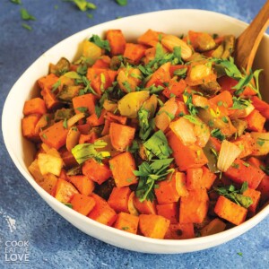 Closeup view of sweet potato hash in a white serving bowl with spoon.