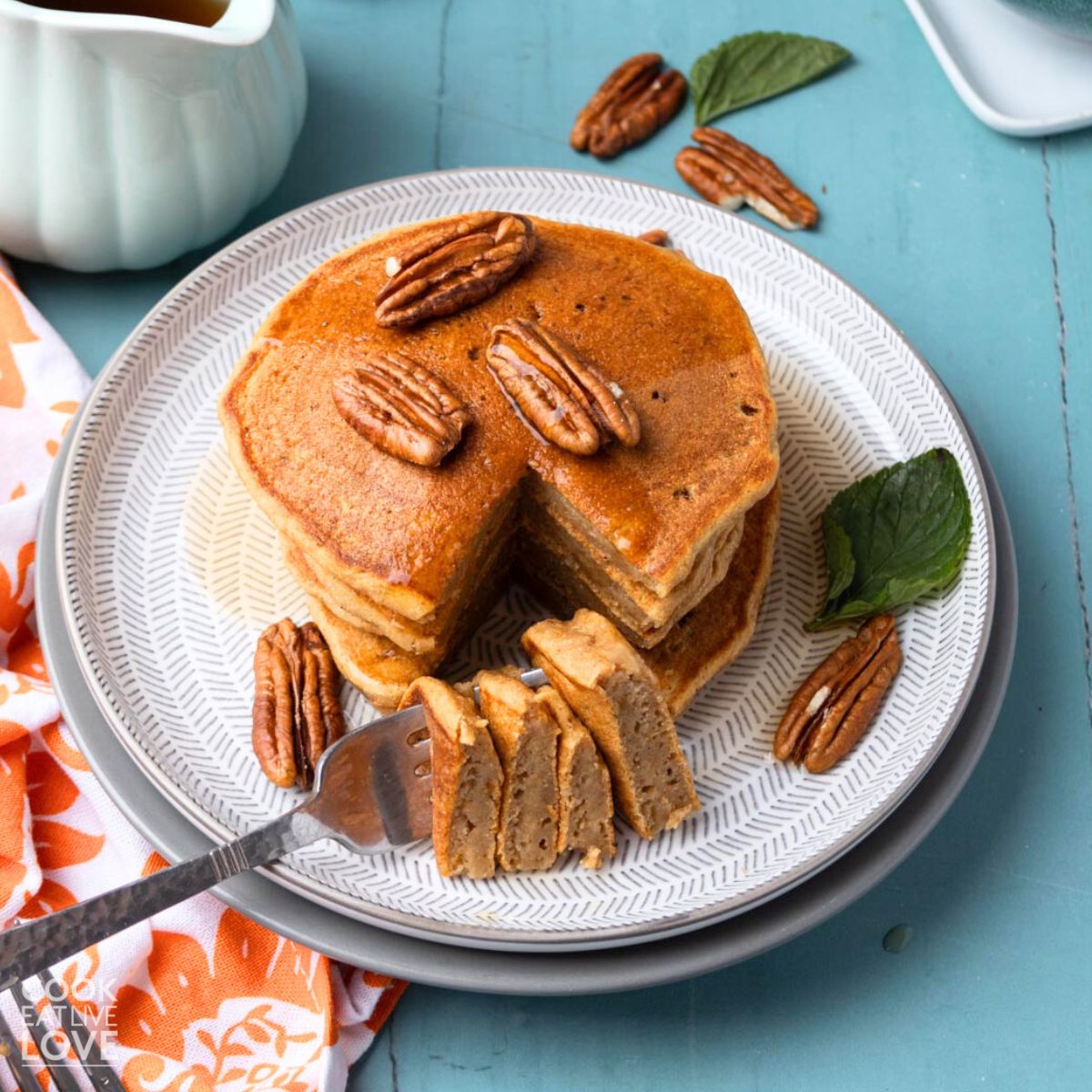 A plate with a stack of sweet potato pancakes with a forkful on the side.