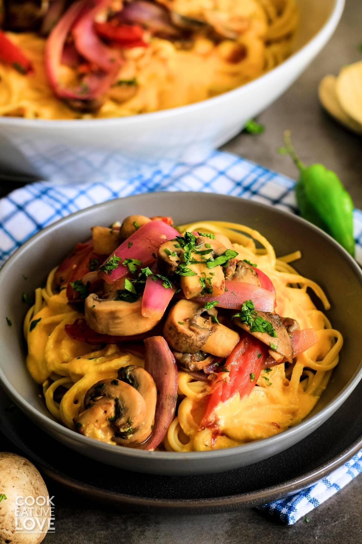 Bowl of pasta with huancaina sauce topped with mushroom saltado.