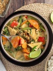 Vegan thai green curry is served up in a bowl with quinoa rice pilaf on the side.