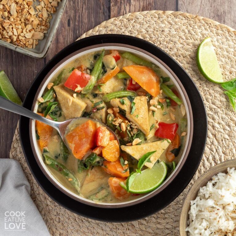 Vegan thai green curry is served up in a bowl with quinoa rice pilaf on the side.