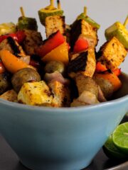 A bowl of tofu and veggies on skewers